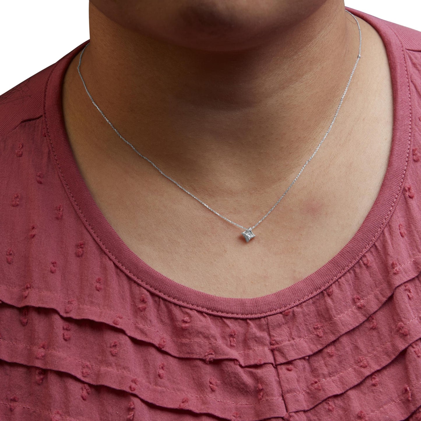 Close-up front view of a white metal necklace with a single princess-shaped pendant featuring one white gemstone, worn on a model wearing a textured red top.