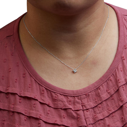 Close-up front view of a white metal necklace with a single princess-shaped pendant featuring one white gemstone, worn on a model wearing a textured red top.