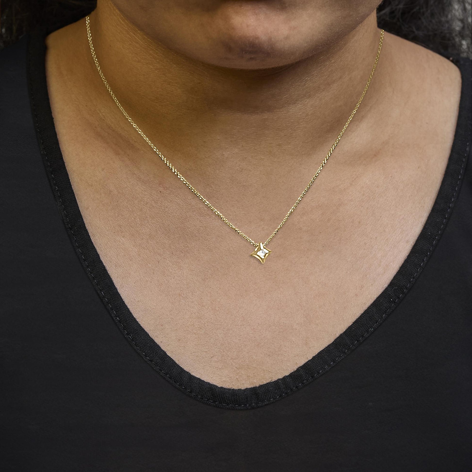 Yellow necklace with a princess-shaped pendant featuring a white gemstone in a bezel setting, shown worn on a model from the front angle.