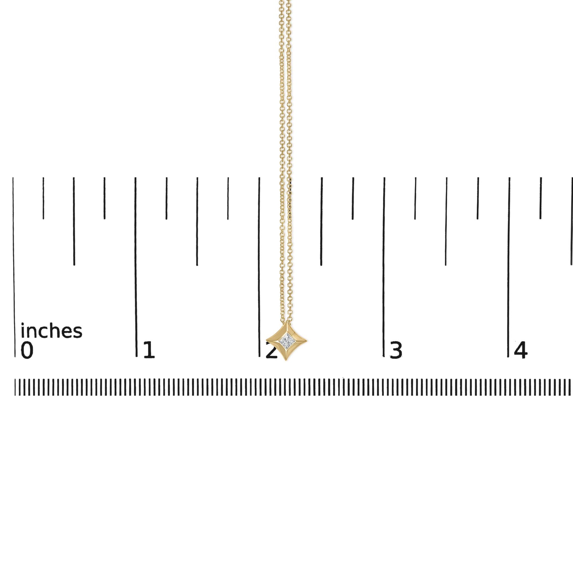 Yellow metal necklace with a small princess shape white gemstone in bezel setting pendant, shown hanging vertically on a scale, front view.