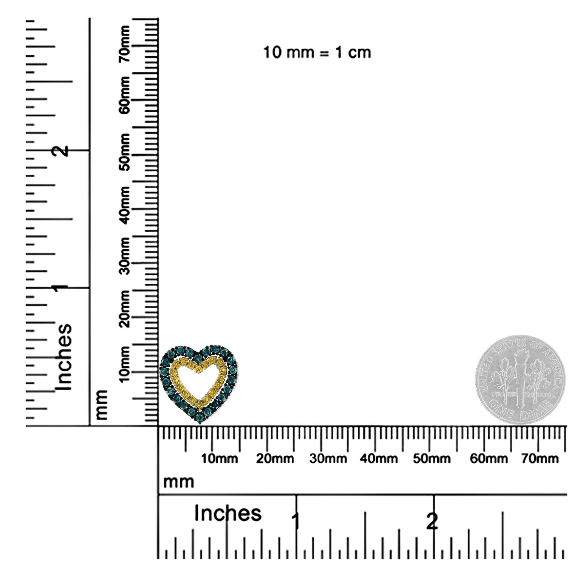 Close-up front angle of a yellow metal heart-shaped necklace pendant with yellow and blue round prong-set gemstones, shown on a ruler and scale for size reference.
