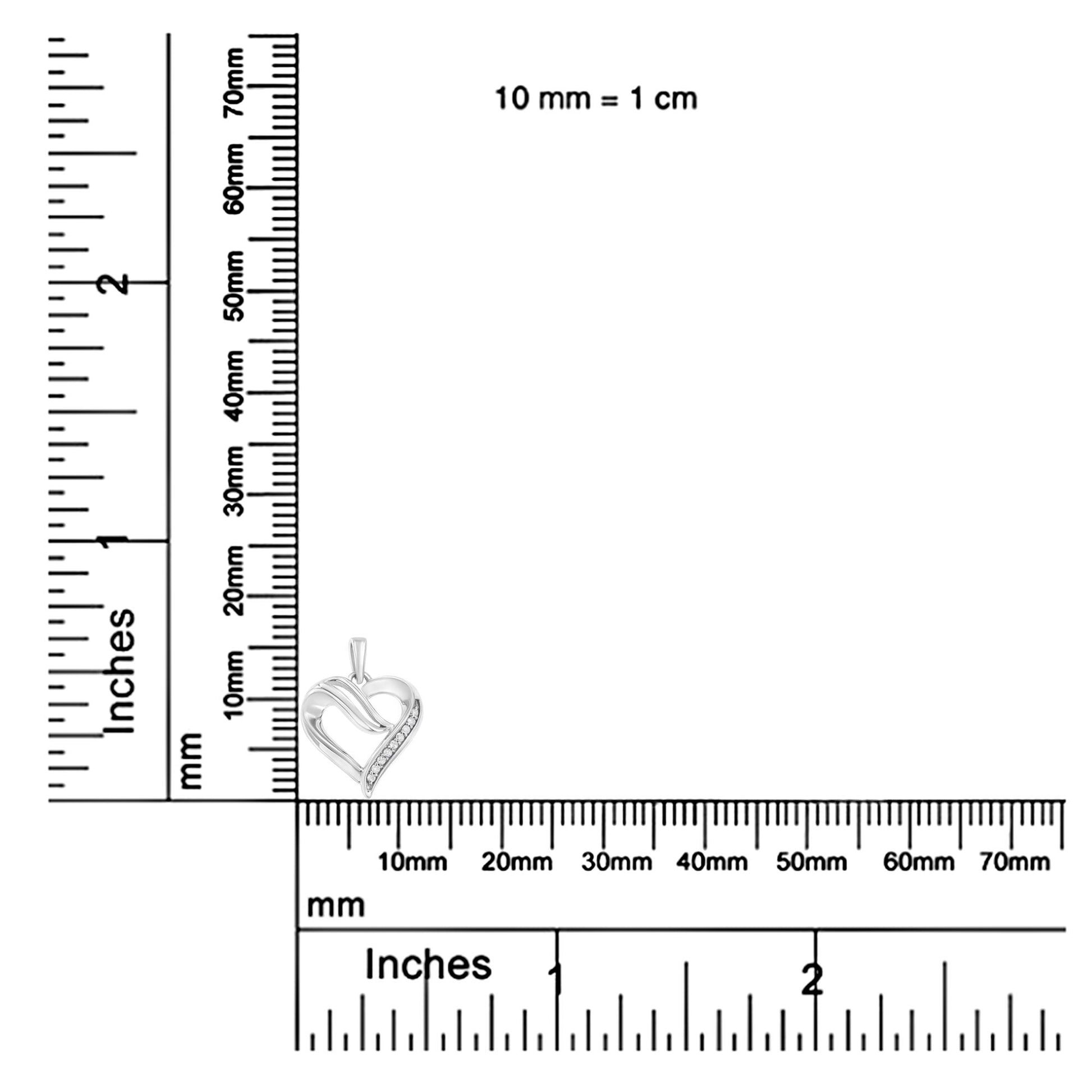 White metal heart-shaped necklace pendant with a row of round white gemstones in prong settings, shown on a ruler for size reference, front angle.