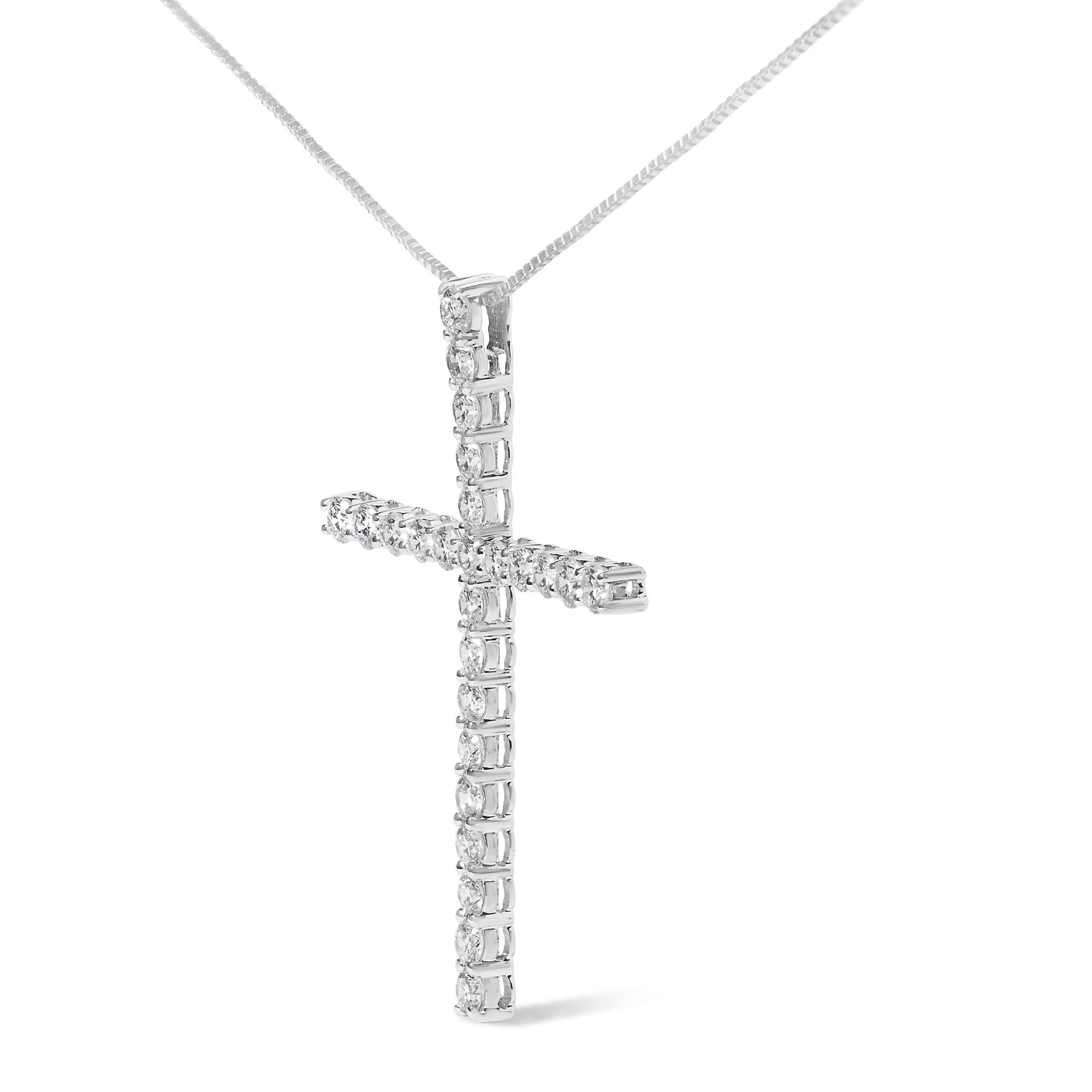 Close-up front angle of a white metal cross-shaped necklace pendant adorned with round white gemstones in prong settings.