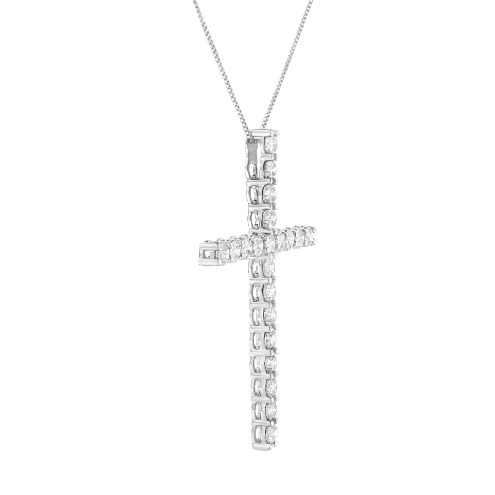Close-up front angle of a white metal cross-shaped necklace pendant adorned with round white gemstones in prong settings.