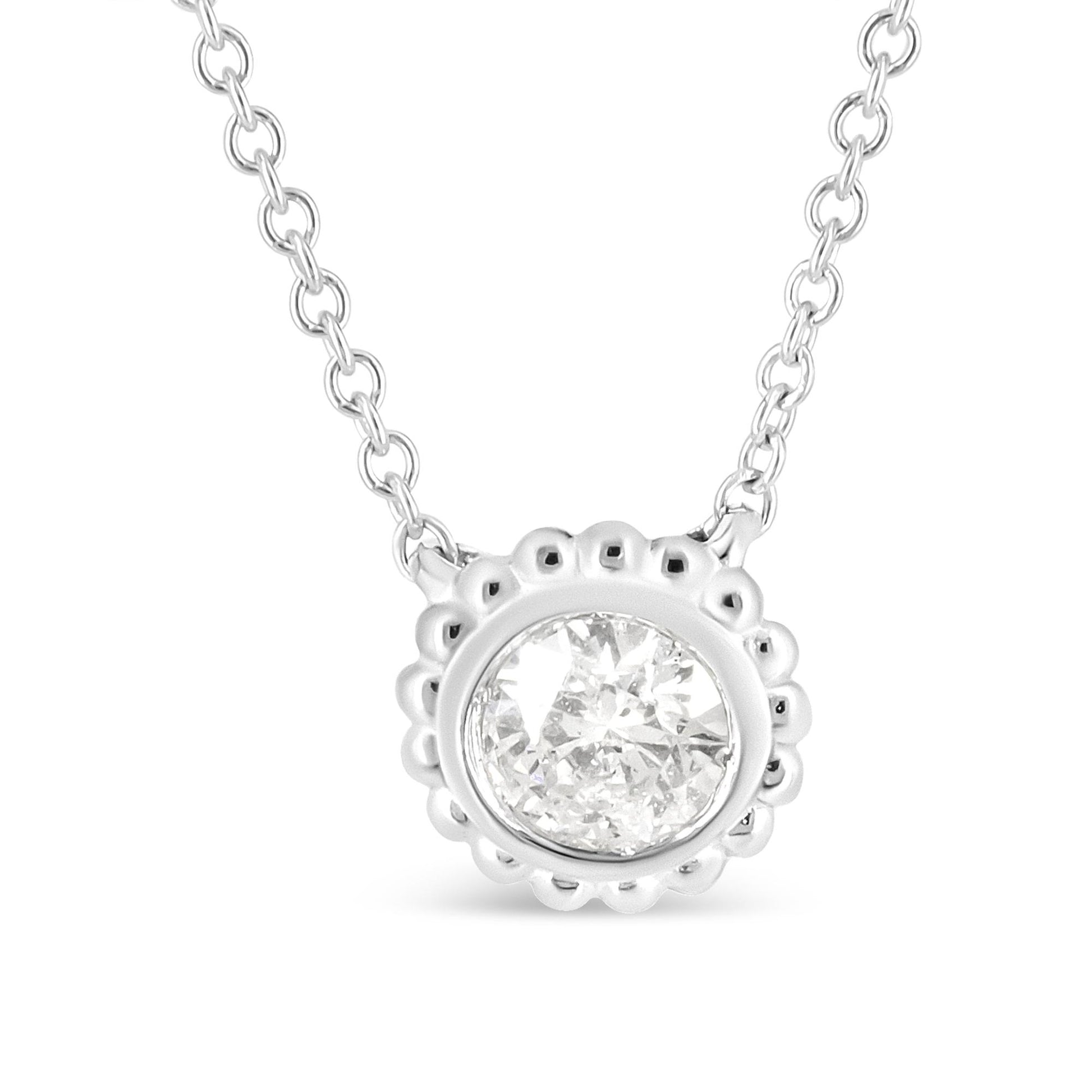 Close-up front view of a white metal necklace with a round bezel-set white gemstone pendant surrounded by a scalloped edge.