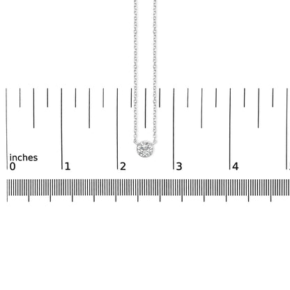 Top-down view of a white metal necklace with a single round white gemstone in bezel setting, placed on a ruler for size reference.
