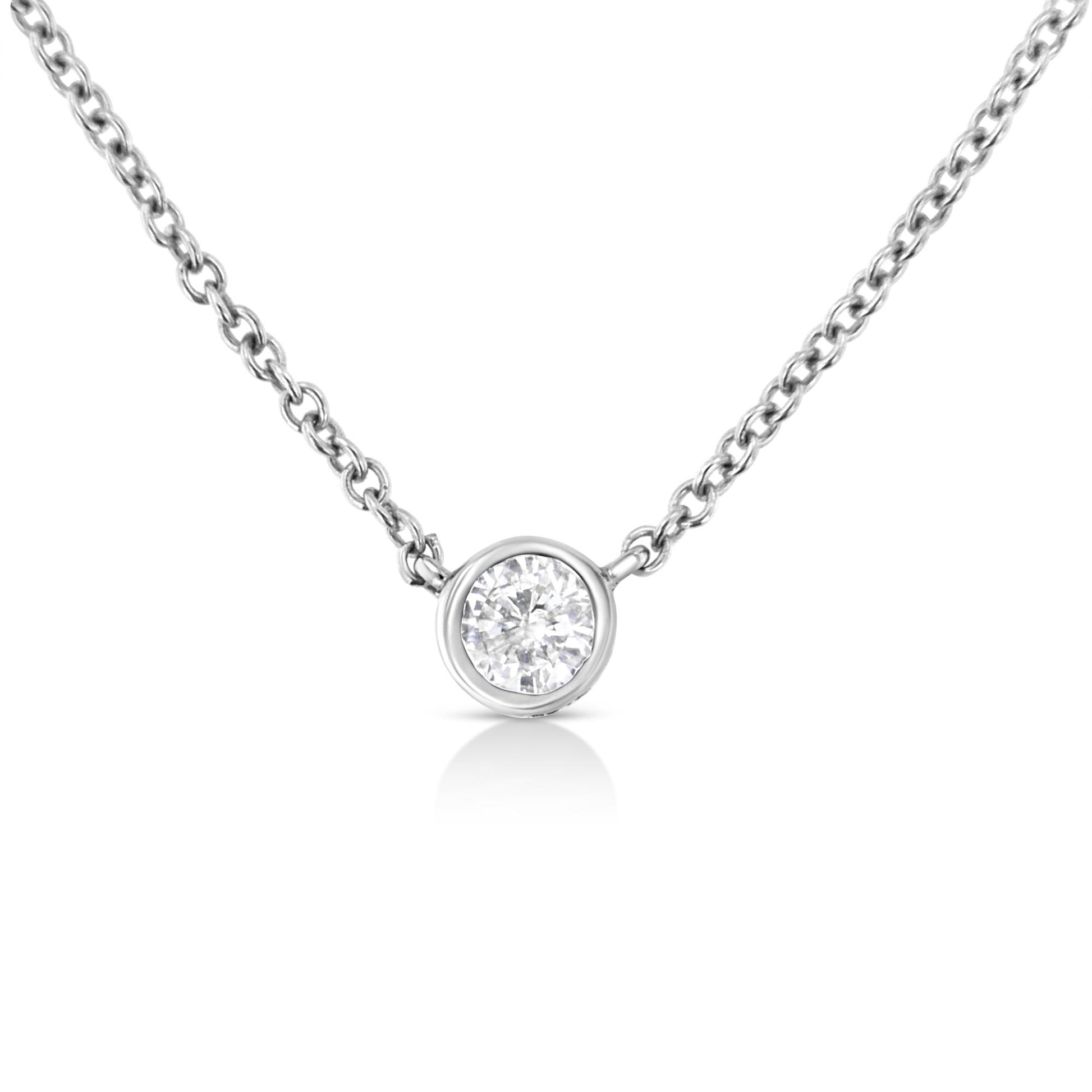 Close-up front view of a white metal necklace with a single round white gemstone in a bezel setting pendant.