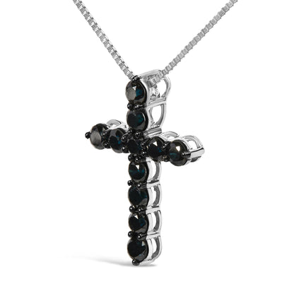 Close-up front angle of a white metal cross-shaped necklace pendant set with round black gemstones in prong settings, suspended from a white metal chain.