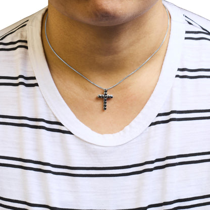 Close-up front view of a white metal necklace with a cross-shaped pendant set with round black gemstones, worn on a model.