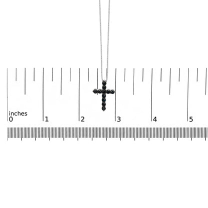 White metal necklace with a cross pendant set with round black gemstones in prong settings, shown hanging above a ruler for size reference, front-facing angle.