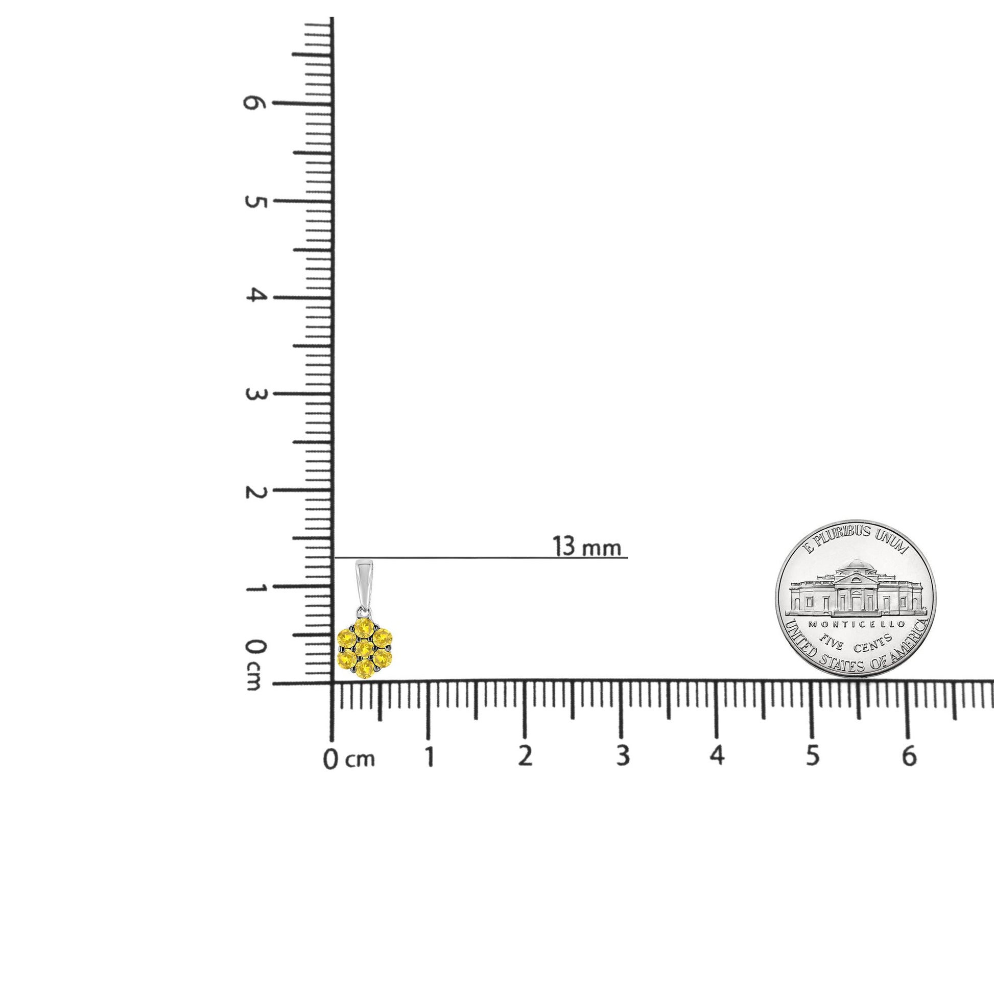 White metal necklace pendant with cluster of round yellow gemstones in prong setting, shown on a ruler for size reference, front angle.