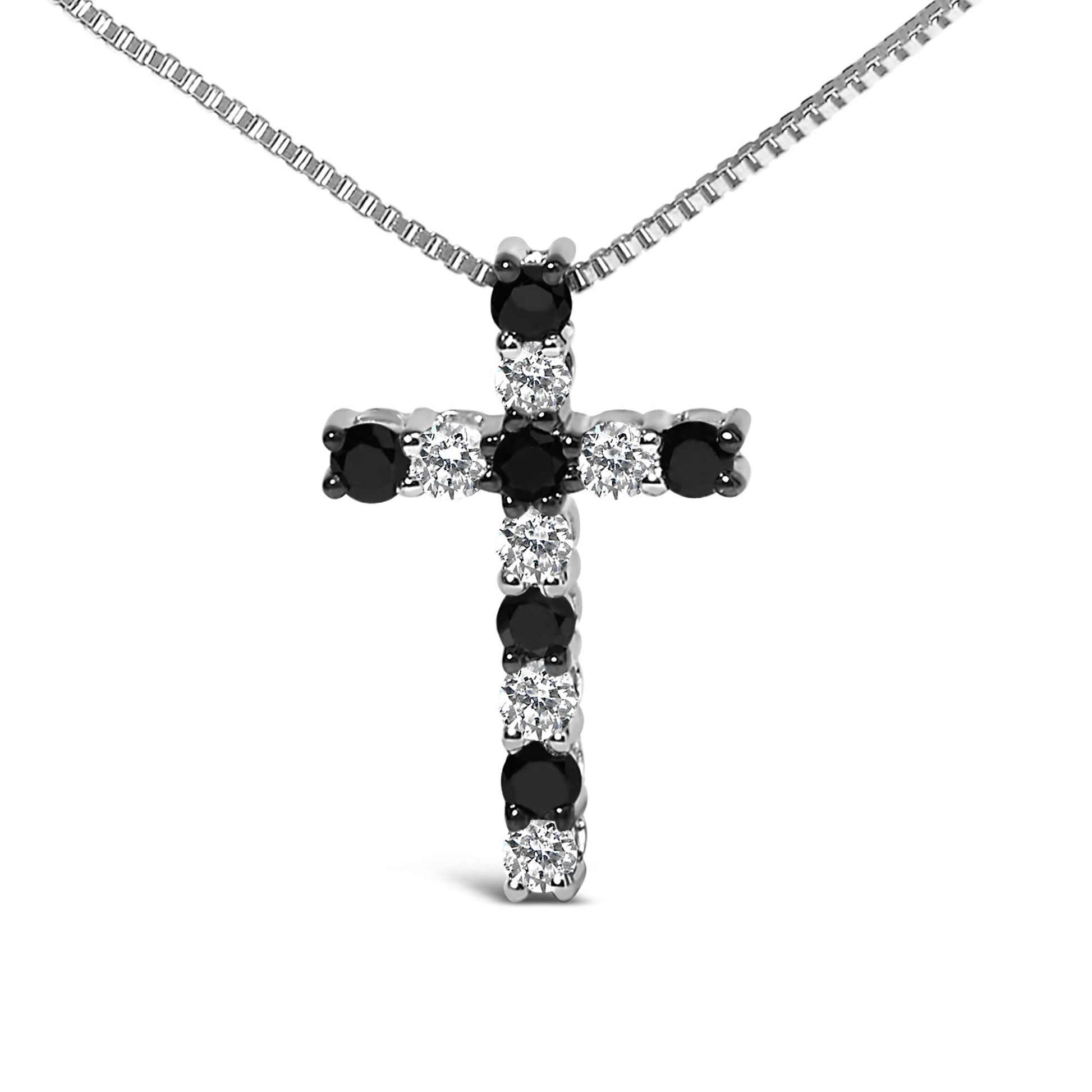 Close-up front view of a white metal cross-shaped necklace pendant with alternating round black and white gemstones in prong settings, hanging on a white metal chain.