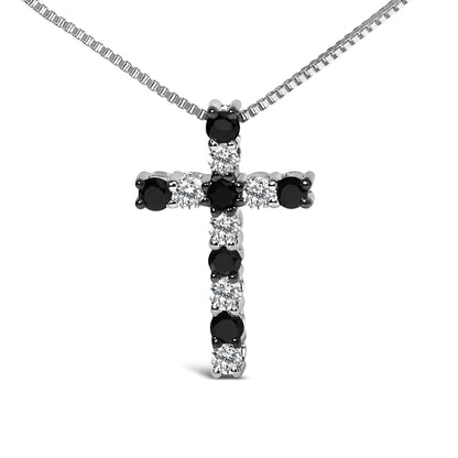 Close-up front view of a white metal cross-shaped necklace pendant with alternating round black and white gemstones in prong settings, hanging on a white metal chain.