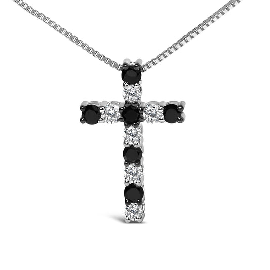 Close-up front view of a white metal cross-shaped necklace pendant with alternating round black and white gemstones in prong settings, hanging on a white metal chain.
