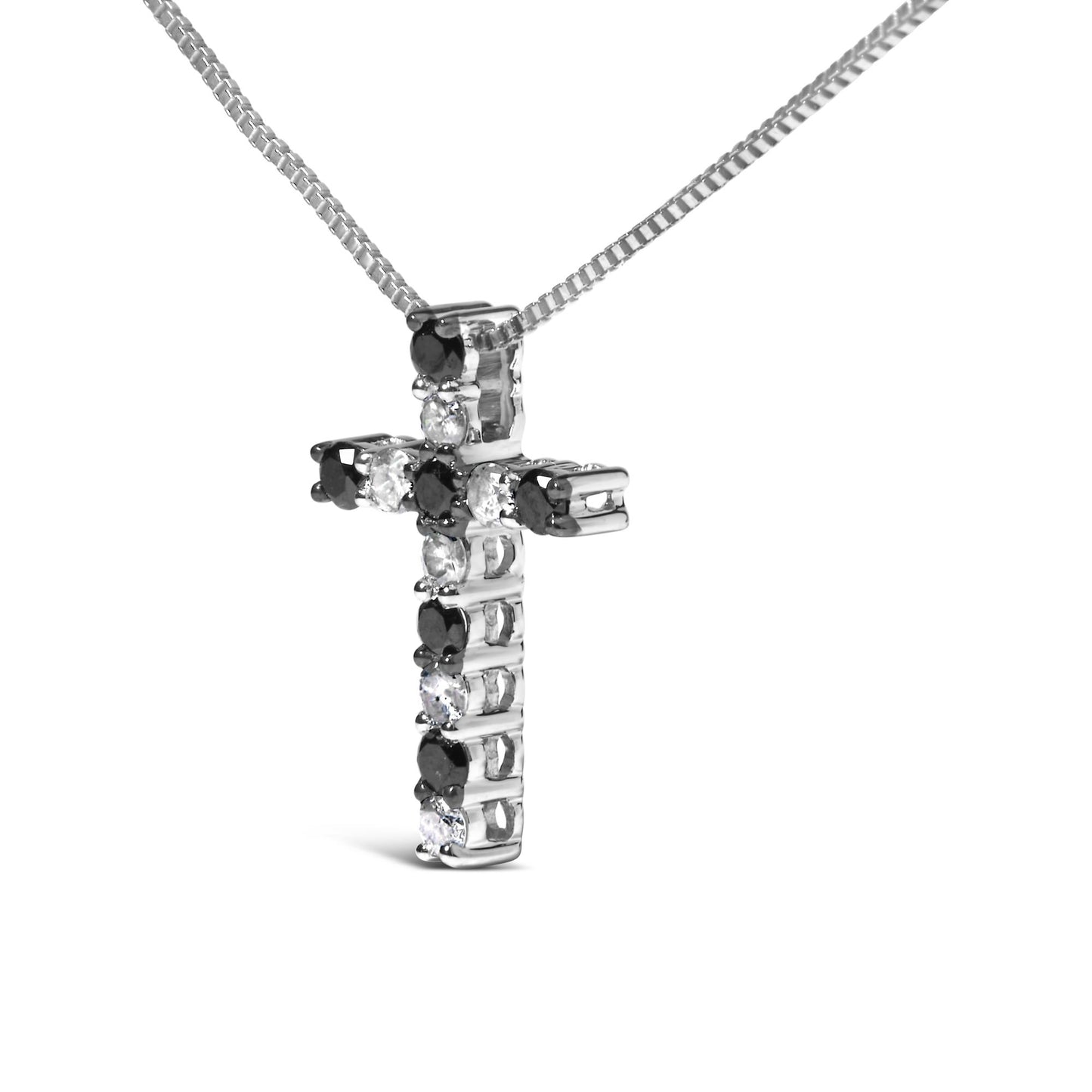 Close-up angled view of a white metal cross-shaped necklace pendant with alternating black and white round prong-set gemstones, hanging from a white metal box chain against a white background.