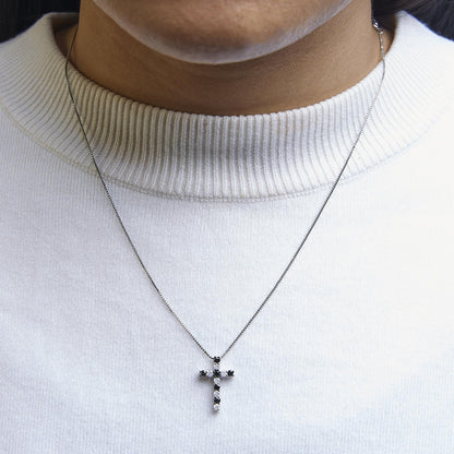 White metal necklace with a cross pendant featuring alternating black and white round gemstones in prong settings, shown worn on a model in a close-up front view.