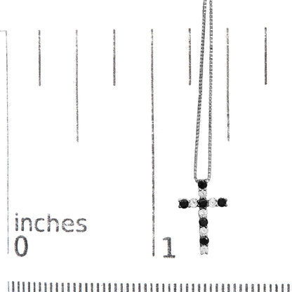 White metal cross-shaped necklace pendant with alternating black and white round gemstones in prong settings, shown hanging on a chain, displayed on a scale at a slight angle.
