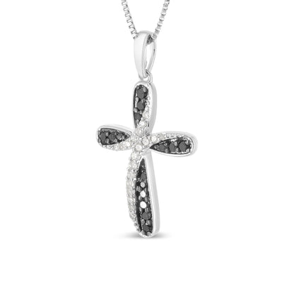 Close-up front angle of a white metal cross-shaped necklace pendant adorned with white and black round gemstones in prong settings.