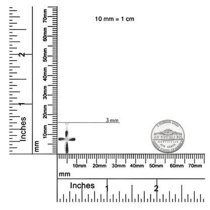 White metal cross-shaped necklace pendant with prong-set white and black round gemstones, shown on a ruler and scale for size reference, front angle.