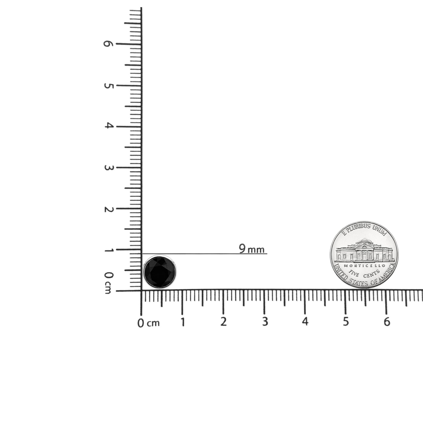 Close-up shot of a round white metal necklace pendant with a bezel-set black gemstone, placed on a ruler for size reference.