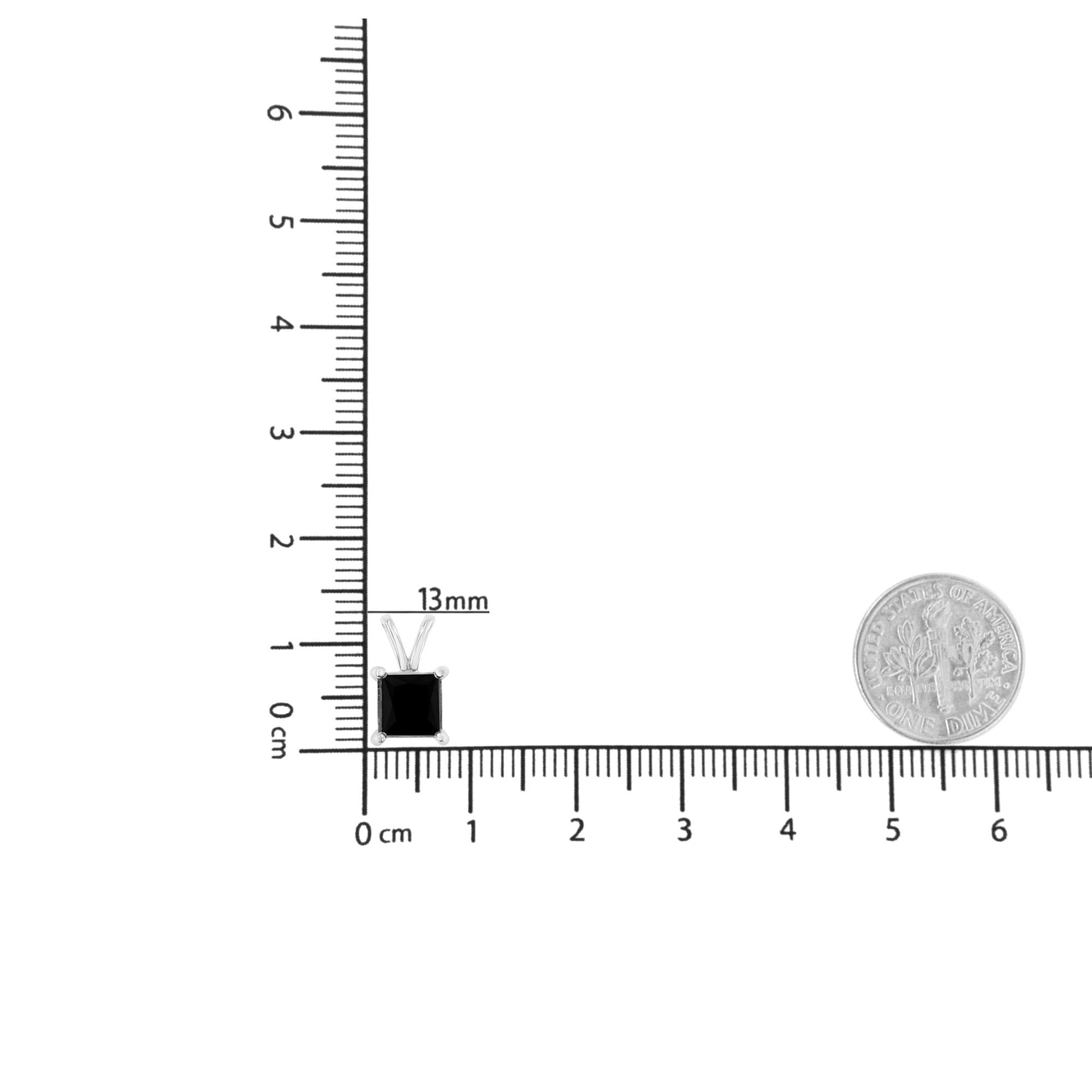 White metal necklace with a princess-shaped black gemstone pendant in prong setting, shown on a ruler and next to a coin for size reference, top-down angle.