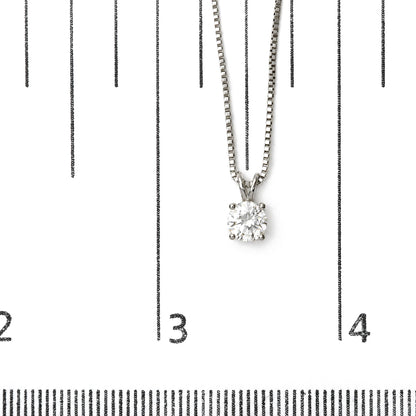 Close-up image of a white necklace with a round white gemstone in a four-prong setting, shown on a scale.