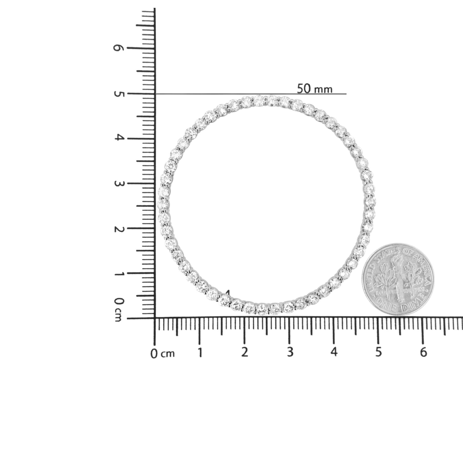 Top-down view of a white metal necklace with round white gemstones in prong settings, displayed on a ruler and next to a coin for size reference.