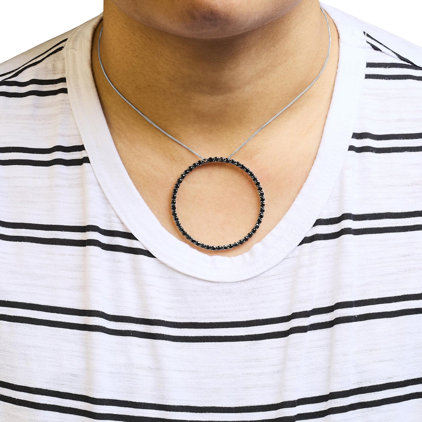 Close-up front view of a white metal necklace with a circular pendant set with round black gemstones worn on a model.