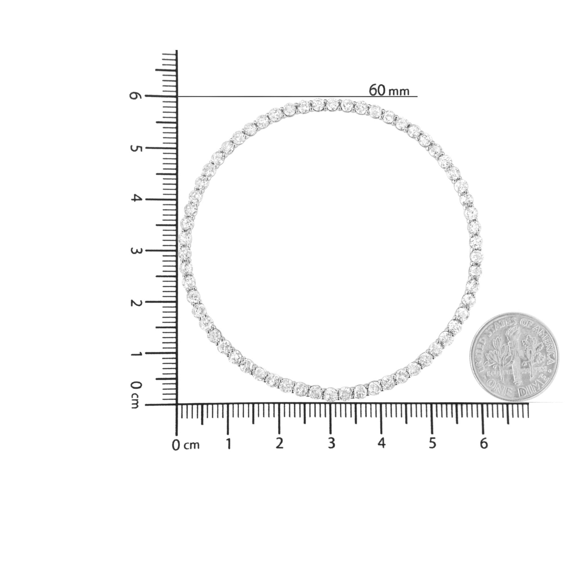 Top-down view of a white metal tennis necklace with round white gemstones in prong settings, displayed on a ruler and next to a dime for size reference.