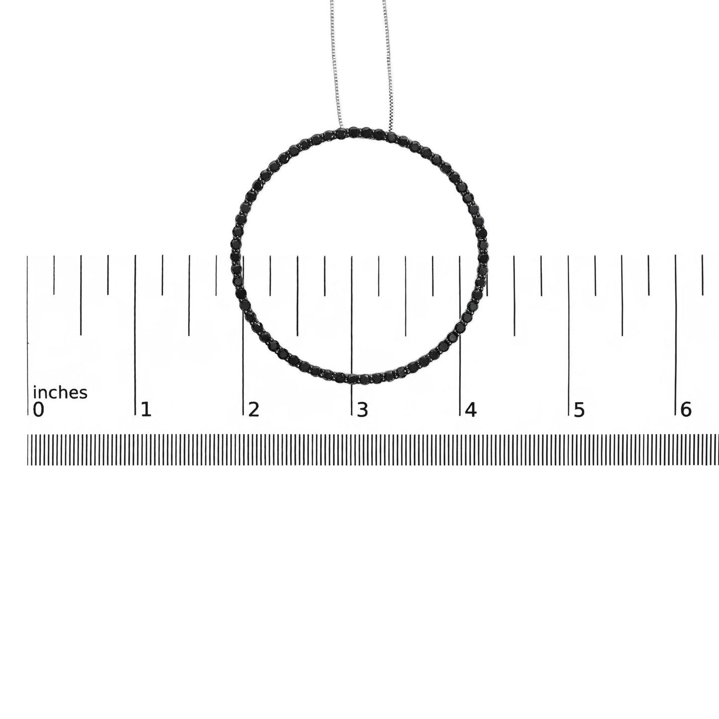 Top-down shot of a white metal necklace with round black gemstones in a shared prong setting, placed on a ruler for size reference.