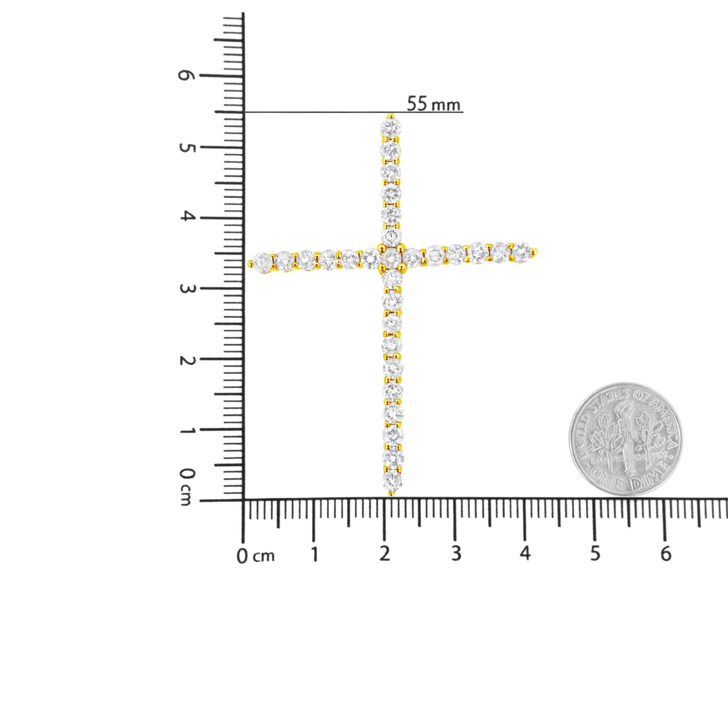 Top-down view of a yellow metal cross-shaped necklace pendant set with round white gemstones, displayed on a ruler and next to a coin for size reference.