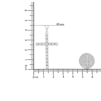 White metal cross-shaped necklace pendant with round prong-set white gemstones, displayed flat on a ruler for size reference, top-down angle.