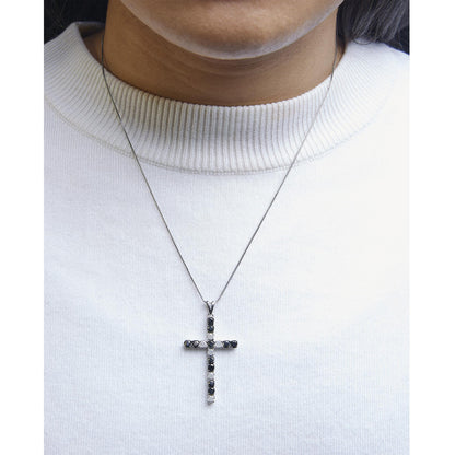 Close-up front view of a white metal necklace on a model, featuring a cross pendant set with alternating round black and white gemstones in prong settings.