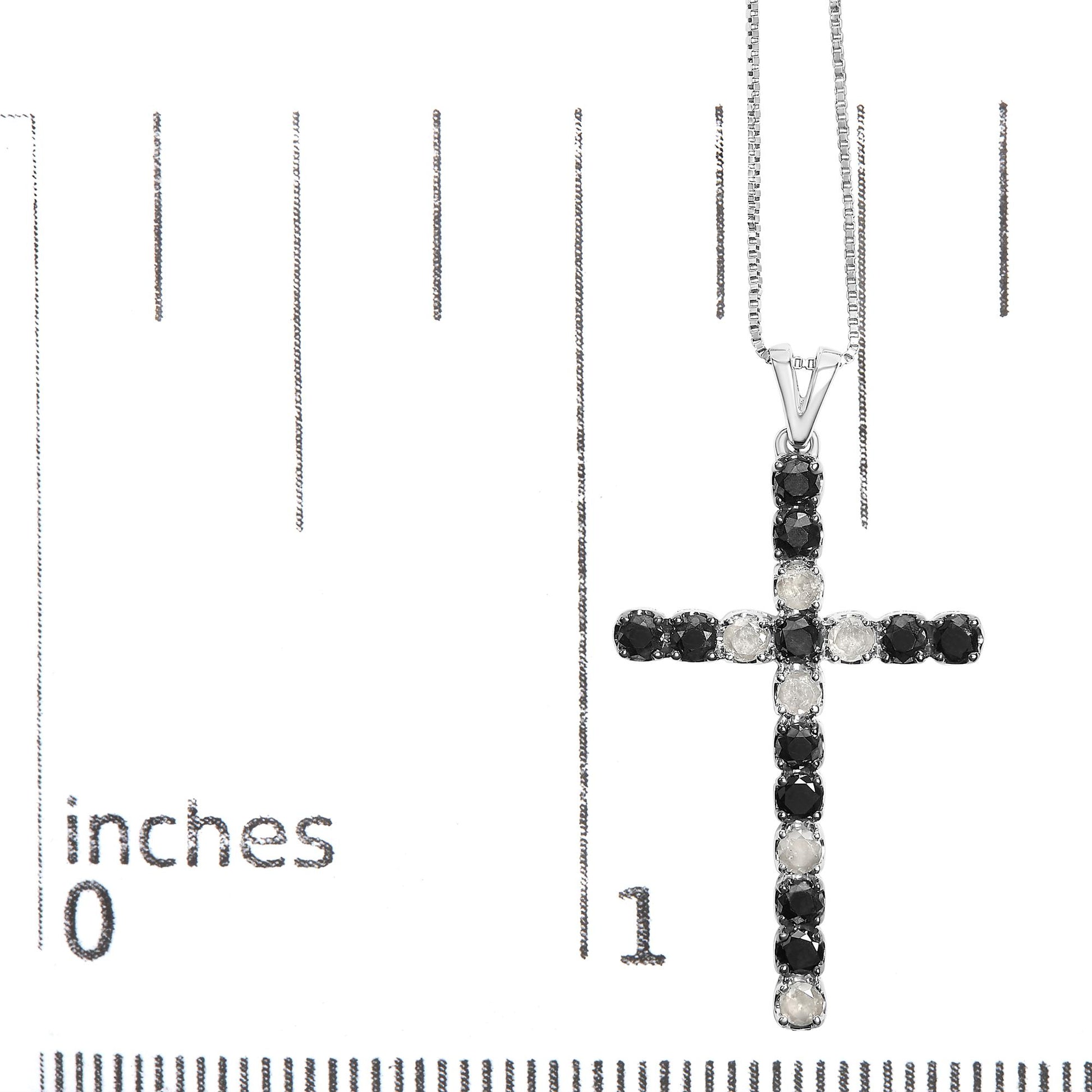 Close-up front view of a white metal cross pendant necklace with alternating black and white round prong-set gemstones, displayed on a ruler for size reference.
