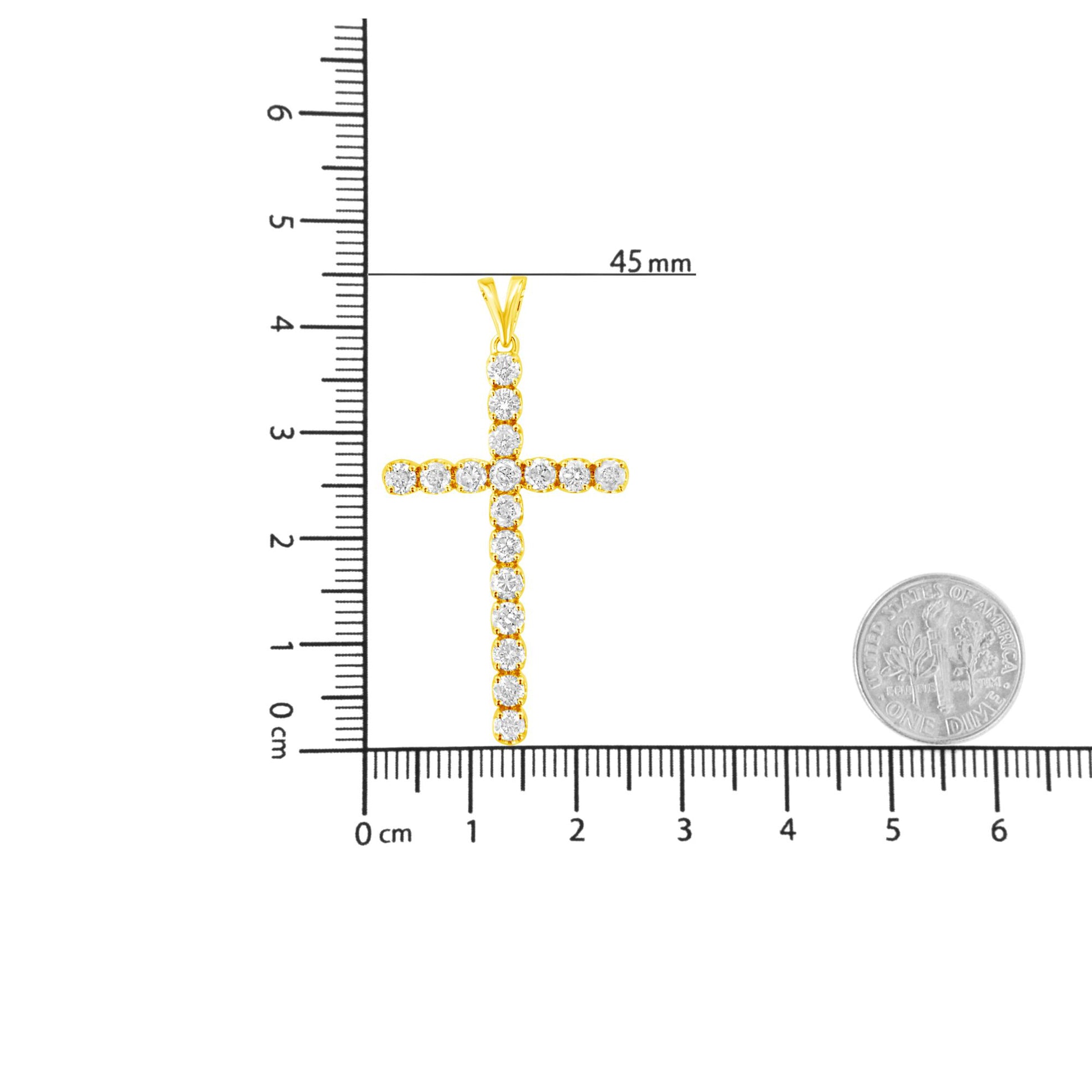Yellow metal cross-shaped necklace pendant with round white gemstones in prong settings, photographed flat on a ruler and scale for size reference.