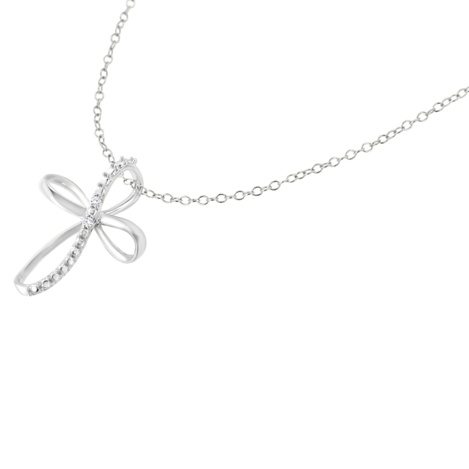Close-up front angle of a white metal necklace with a pendant shaped like a stylized cross featuring two white round gemstones in prong settings.