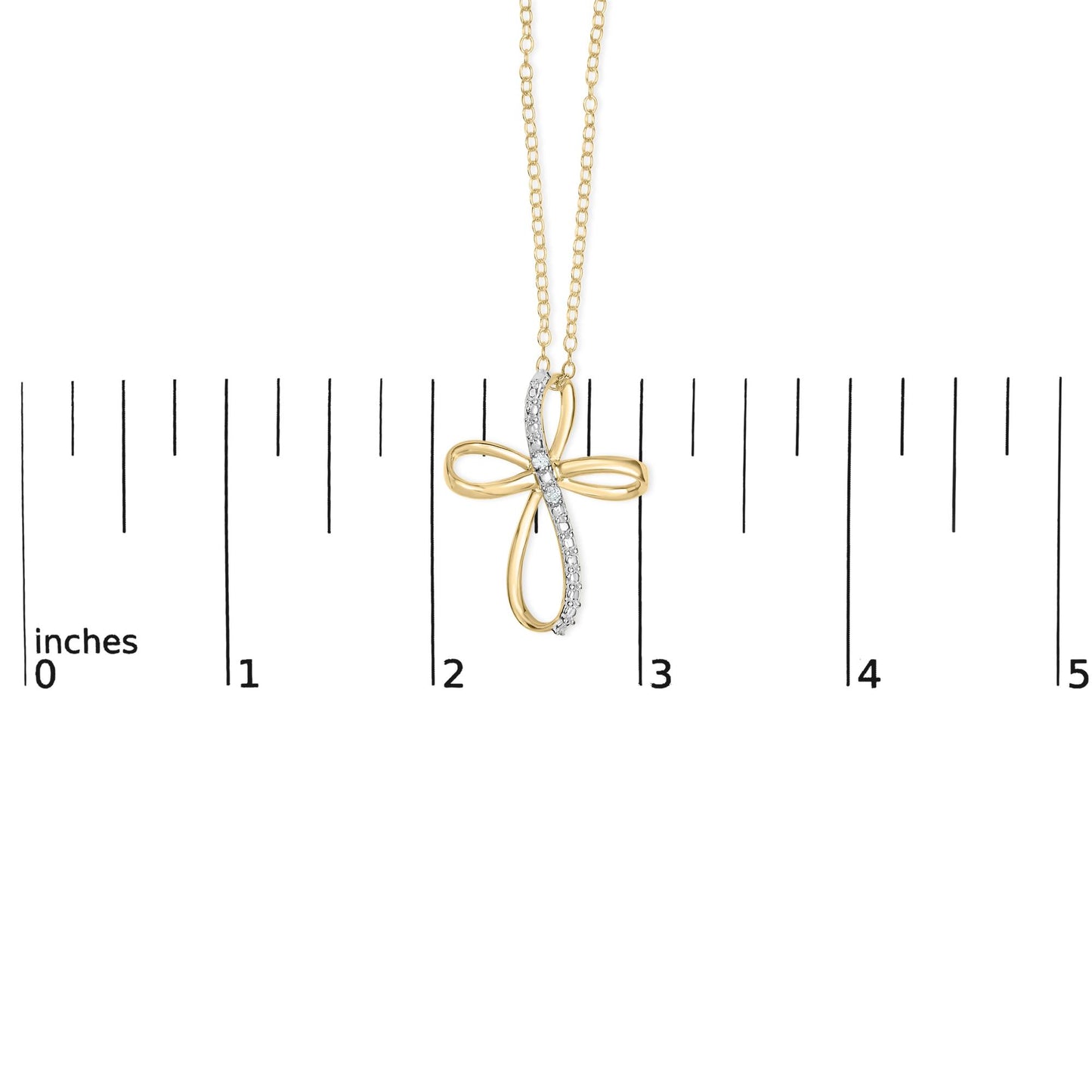 Yellow metal cross-shaped necklace pendant with a row of white gemstones along one arm, shown from the front hanging on a chain against a ruler for size reference.