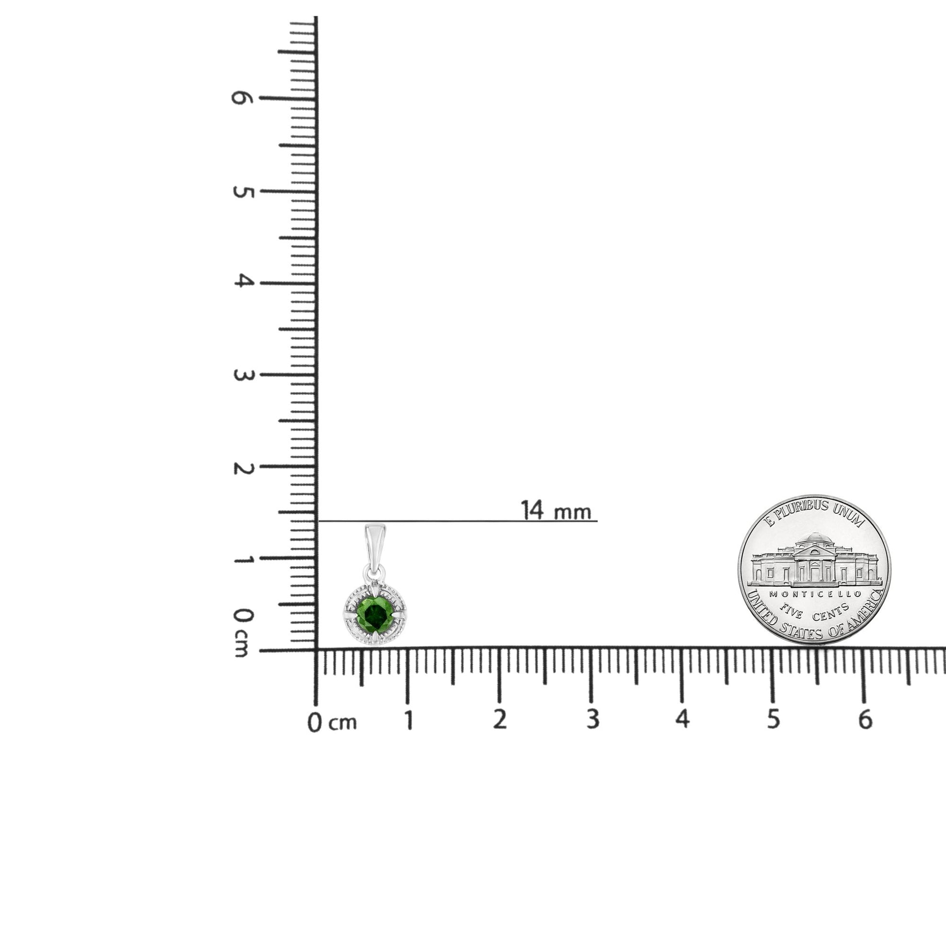 Close-up front angle of a white metal necklace pendant with a round green gemstone surrounded by a halo of small black gemstones, displayed on a ruler for size reference.