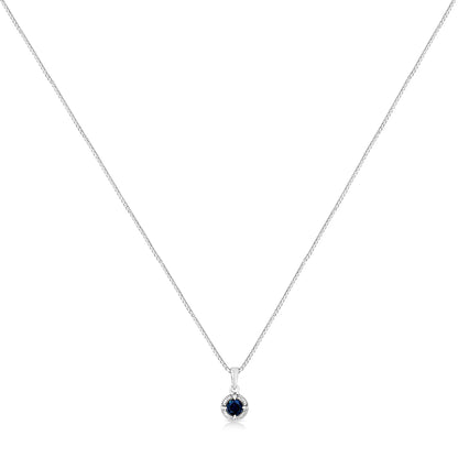 Front-facing shot of a white metal necklace with a round blue gemstone pendant in a four-prong setting.