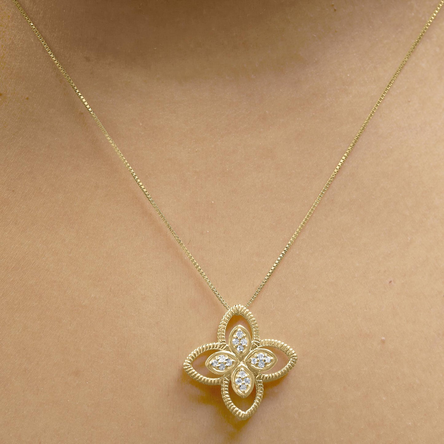 Yellow metal necklace with a flower-shaped pendant featuring white round gemstones in prong settings, worn on a model, front-facing angle.