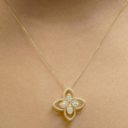 Yellow metal necklace with a flower-shaped pendant featuring white round gemstones in prong settings, worn on a model, front-facing angle.