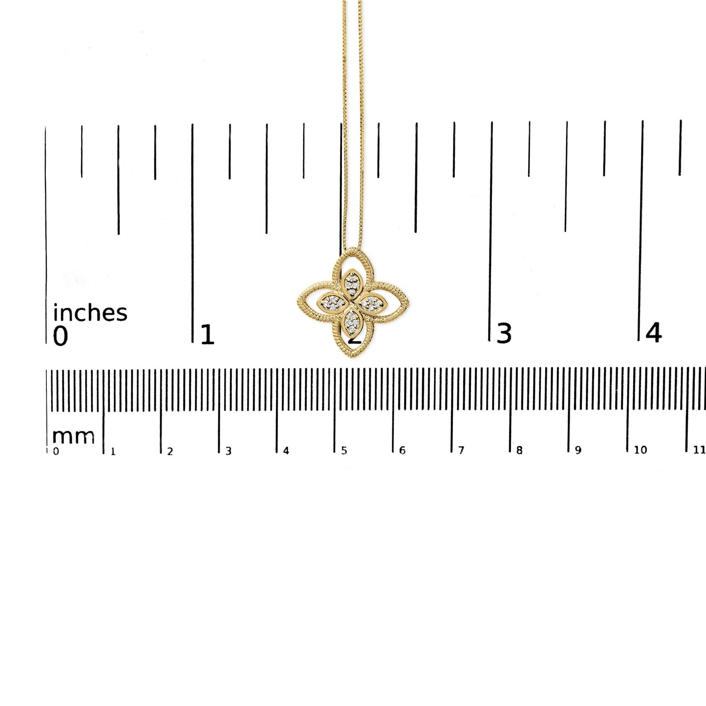 Yellow metal necklace with a flower-shaped pendant featuring white round gemstones in prong settings, shown from the front on a ruler for size reference.