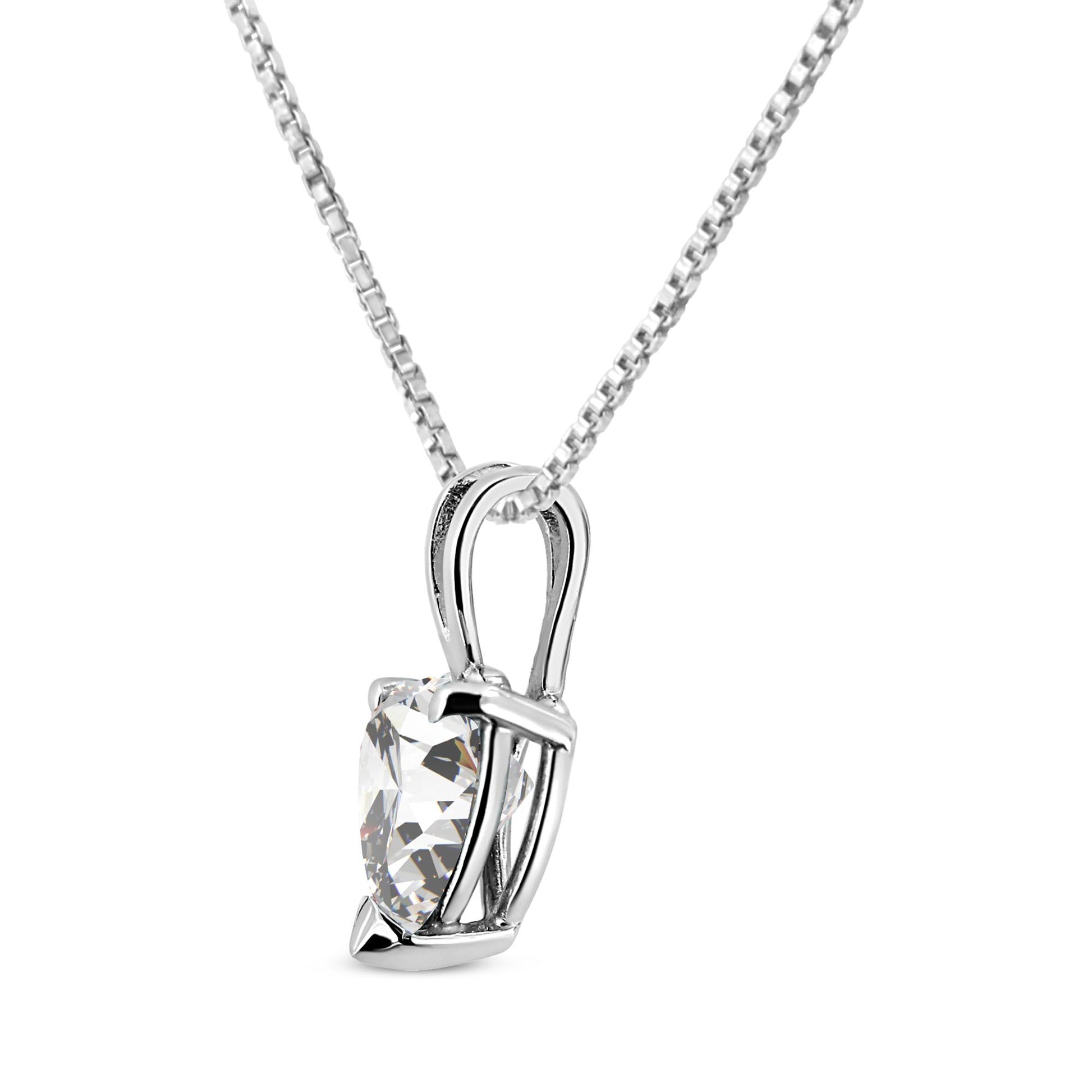 Close-up angled view of a white metal necklace with a heart-shaped white gemstone in a three-prong setting.
