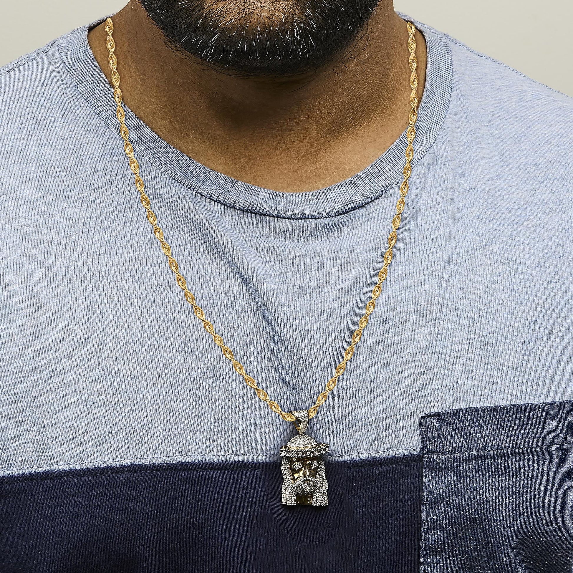 Yellow metal necklace with a pendant featuring white gemstones in pave setting, shown worn on a model from a front view angle.
