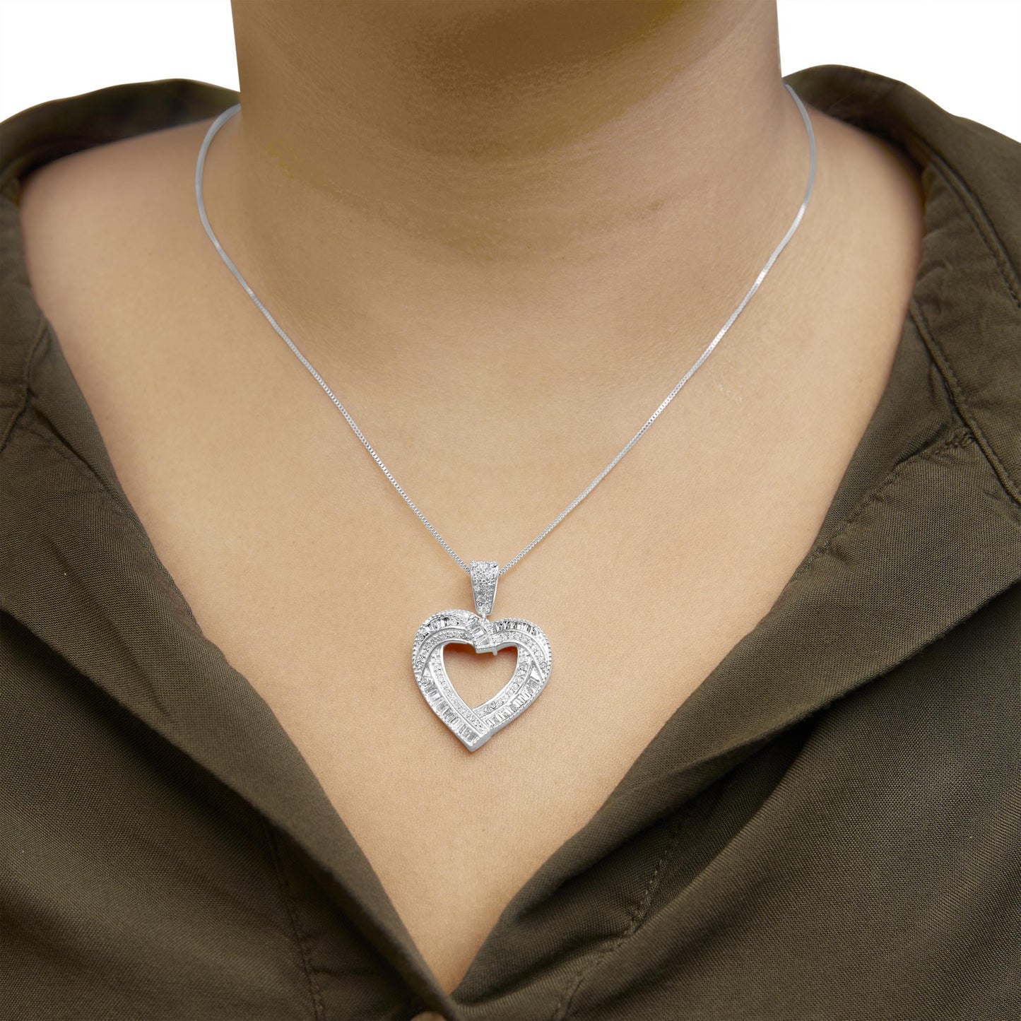 White metal heart-shaped pendant necklace with round and baguette white gemstones, shown worn on a model, close-up front angle.