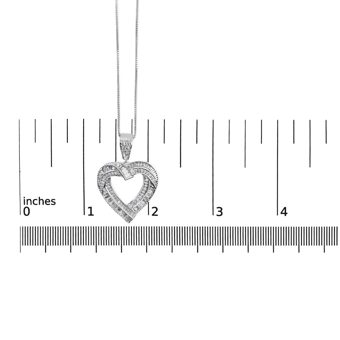 Close-up front view of a white metal heart-shaped necklace pendant with round white gemstones in prong settings and baguette white gemstones in channel settings, shown on a measurement scale.