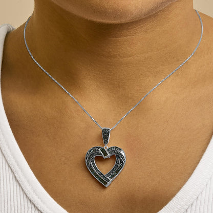 Necklace with a heart-shaped pendant featuring blue round prong and baguette channel-set gemstones on a white metal chain, shown worn on a model in a close-up frontal shot.