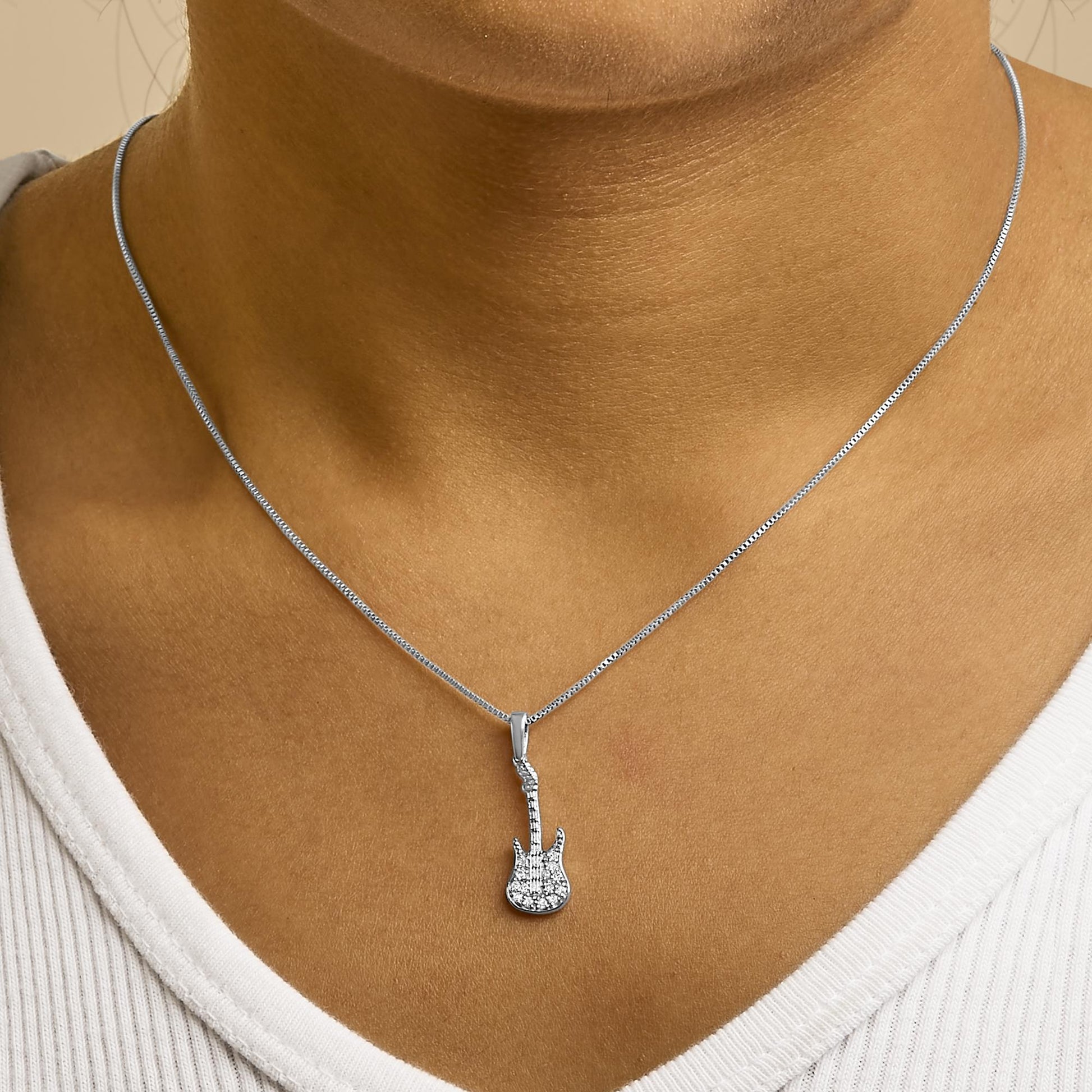 Necklace with guitar-shaped pendant featuring round white gemstones in prong setting, shown worn on a model, front view.