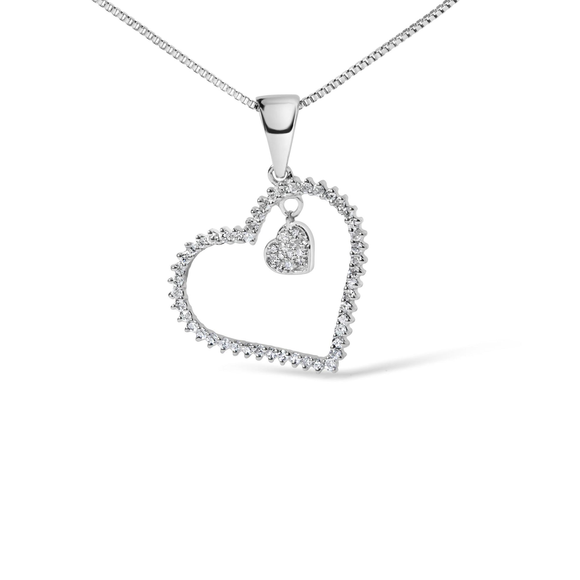 Close-up front view of a white necklace pendant featuring an open heart outline with round white gemstones in a prong setting, and a smaller solid heart charm encrusted with round white gemstones hanging inside the larger heart.