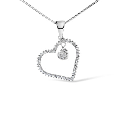 Close-up front view of a white necklace pendant featuring an open heart outline with round white gemstones in a prong setting, and a smaller solid heart charm encrusted with round white gemstones hanging inside the larger heart.